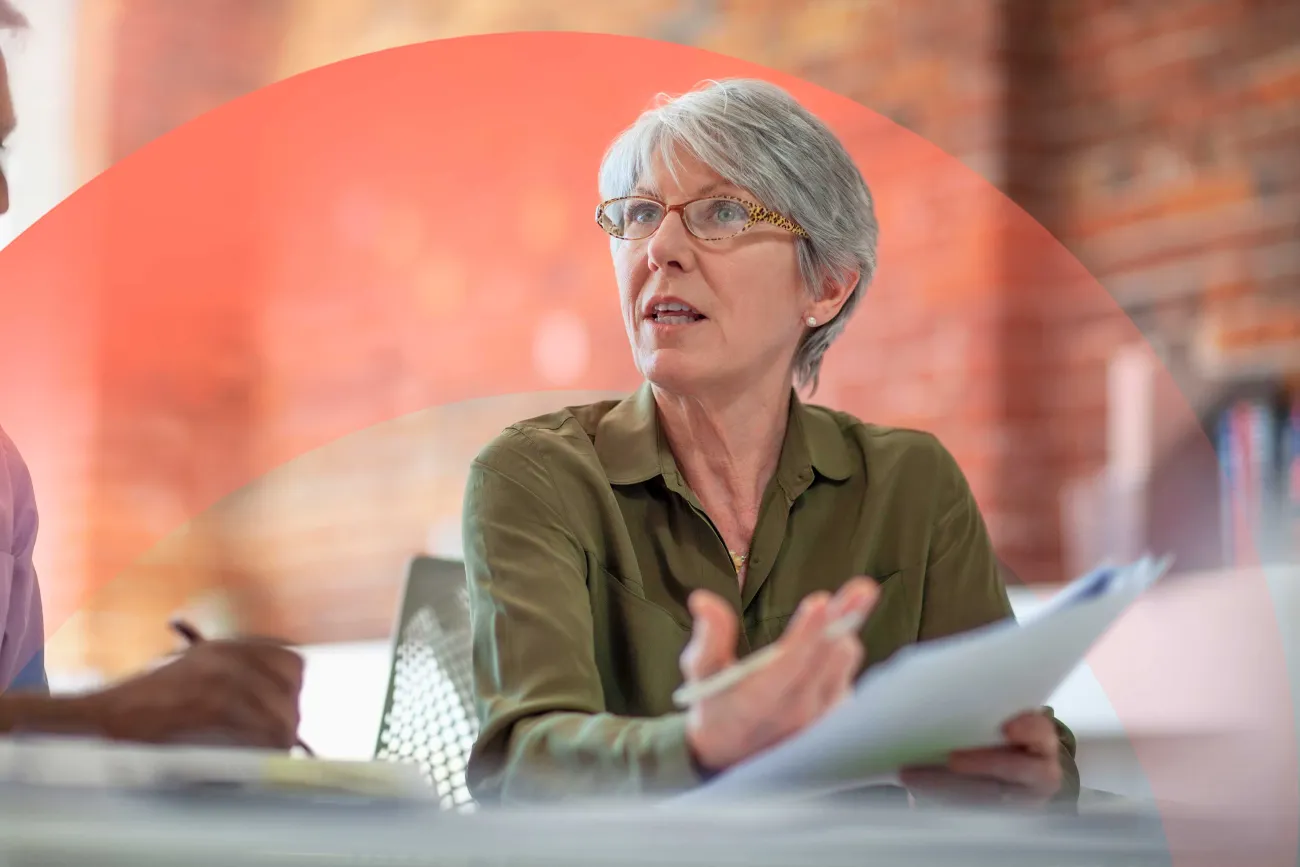 Professional woman speaking to someone, reviewing and holding a paper document.