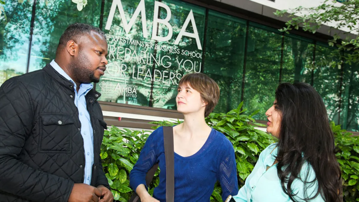 3 people having a conversation outside a glass building