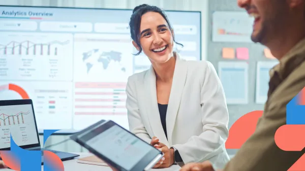 Business professionals reviewing data on tablets while smiling, surrounded by colorful analytics charts