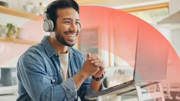 Smiling professional participating in a video meeting on a laptop from home, and wearing headphones