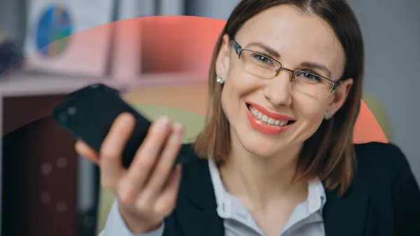 Smiling businesswoman holding a phone, and smiling at the camera.