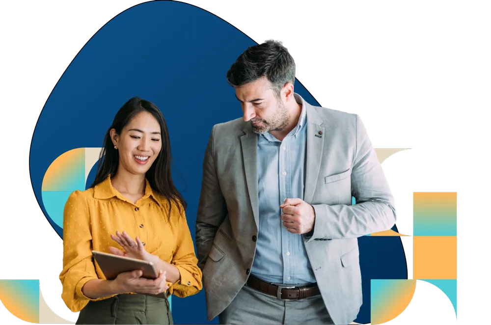 Two professionals in casual business attire review information on a tablet against colorful background